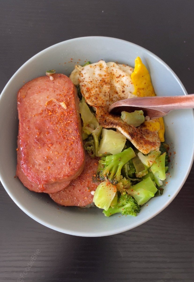 picture of a light blue bowl with spam with rice and broccoli on a black wood background